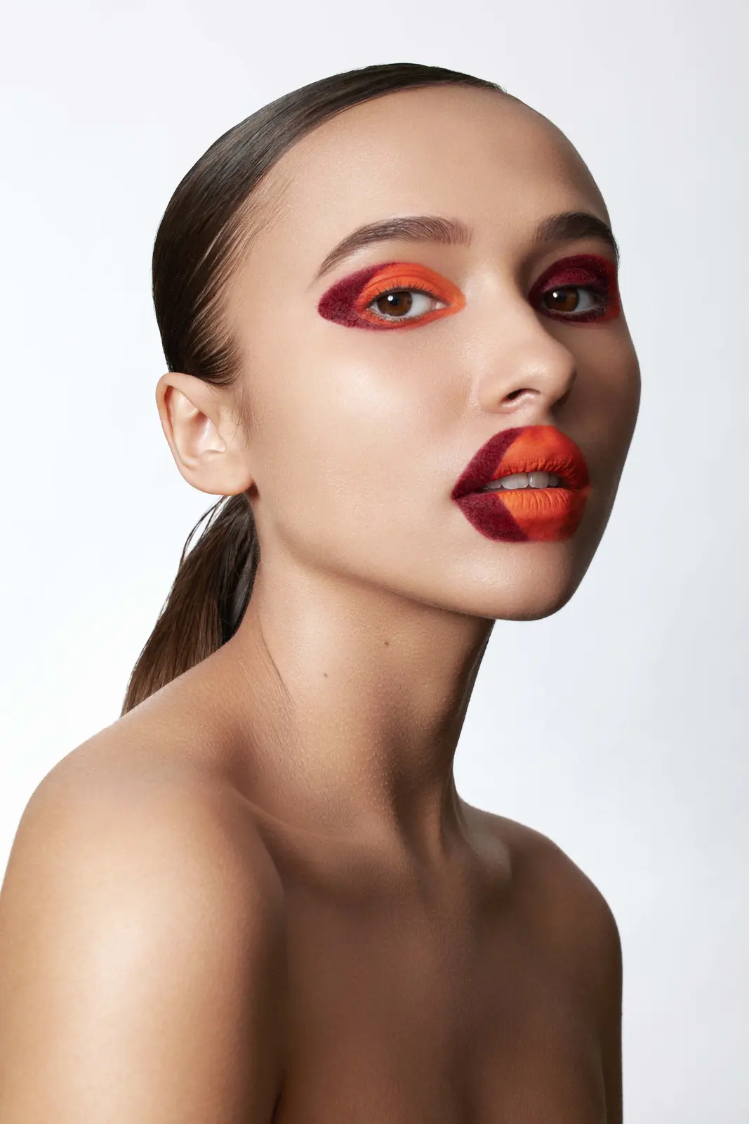 Portrait studio : paupières rouge et orange, lèvres bicolores, chignon plaqué