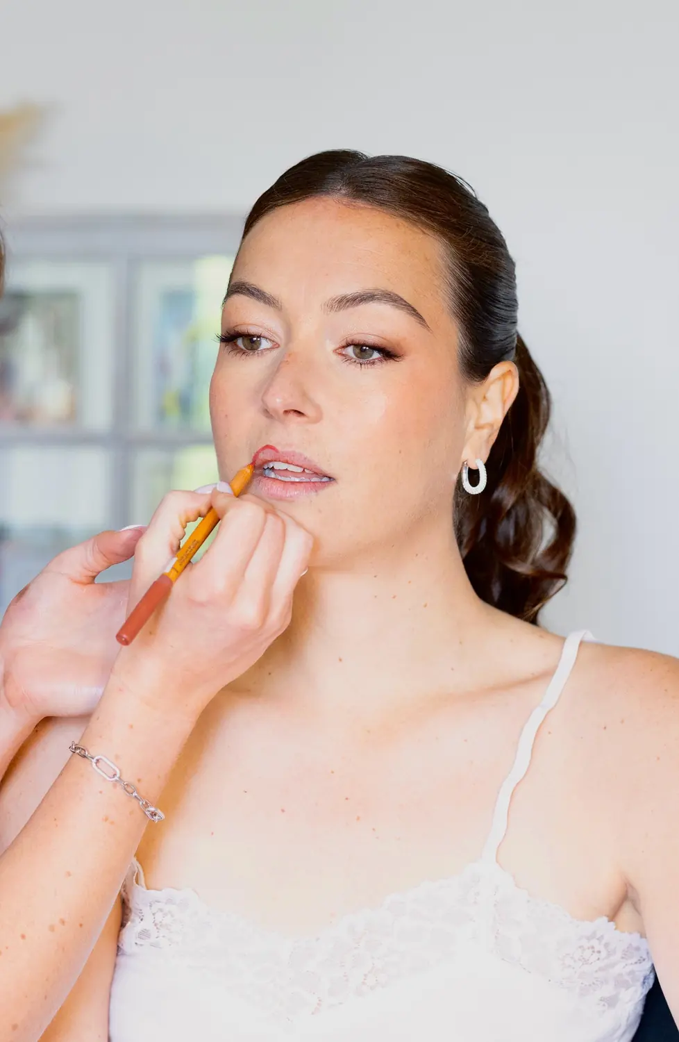 Application d’un crayon à lèvres sur une mariée en caraco de dentelle